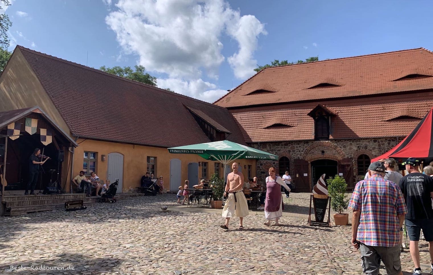 Gastronomie im Burghof von Burg Rabenstein: Imbiss-Stand, Biergarten, Bühne mit Musiker und Personal in mittelalterlicher Bekleidung