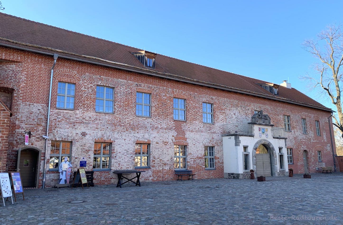 Burg Storkow, Teil vom Innenhof: Besucher-Informationszentrum (BIZ) vom Naturpark Dahme-Heideseen, Gastronomie und mit Wappen geschmückter Eingang