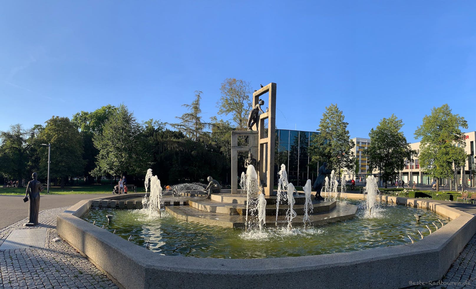 Markanter Brunnen am Stadtpark Dessau, dahinter verspiegeltes Gebäude: Bauhausmuseum
