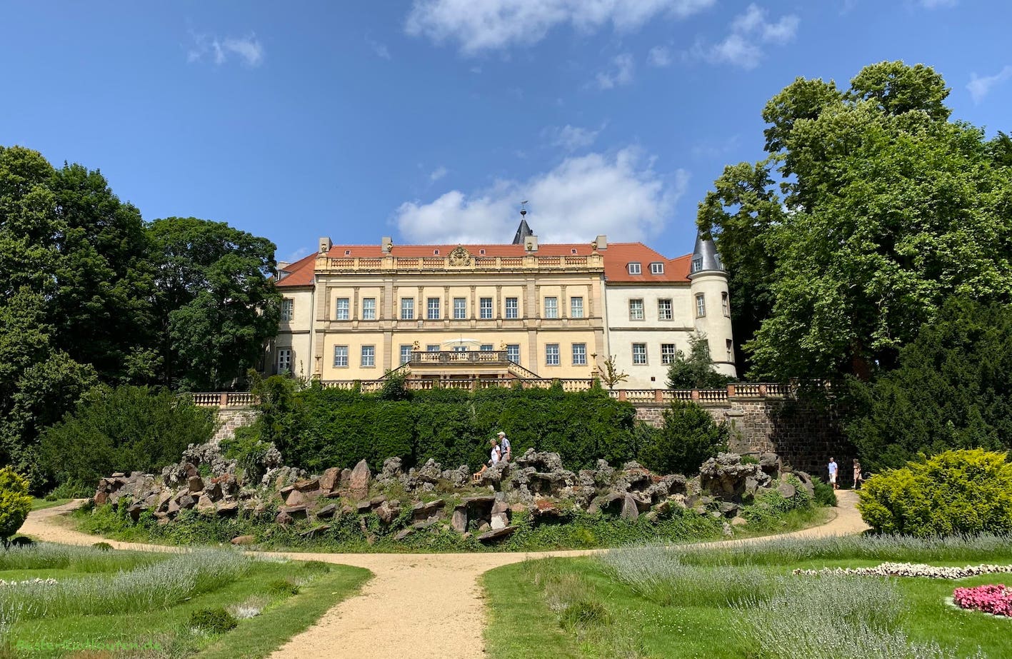 Schloss Wiesenburg, Foto vom Süden her, davor ein Brunnen aus Natursteinen