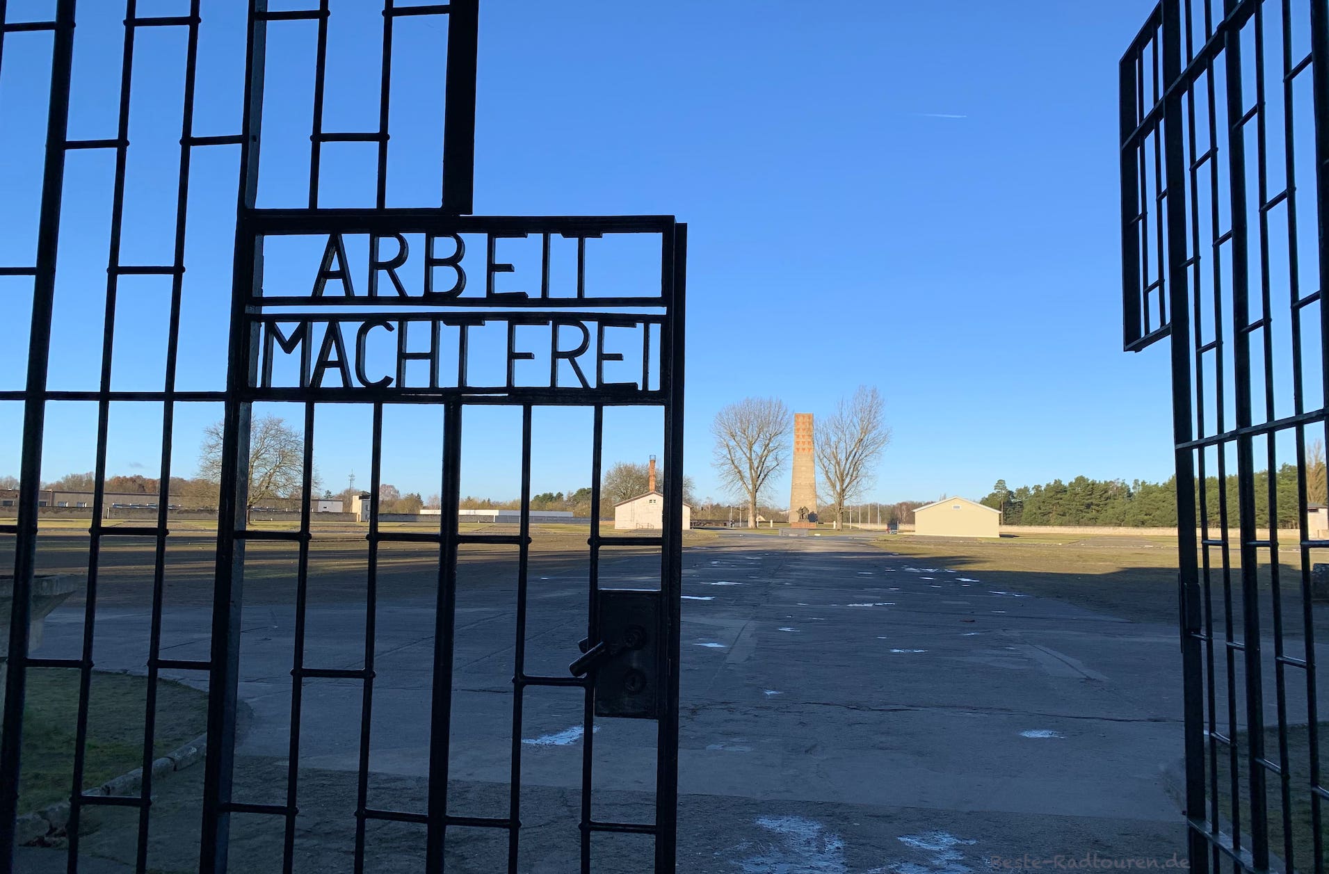 Foto von außen: Eingang vom Konzentrationslager Sachsenhausen, Aufschrift "Arbeit macht frei", Blick auf den Appellplatz