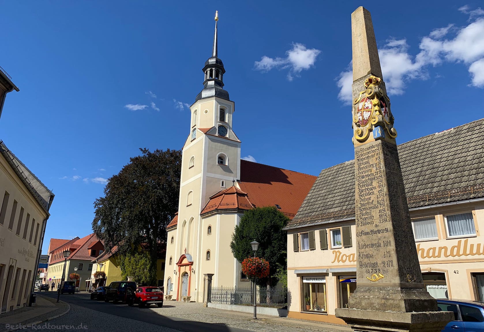 Foto im Zentrum von Elsterwerda: Postmeilensäule und Kirche St. Katharina